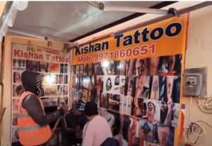 Exterior of a tattoo shop on Ram Path in Ayodhya, featuring various tattoo design options and a sign indicating custom body art services.